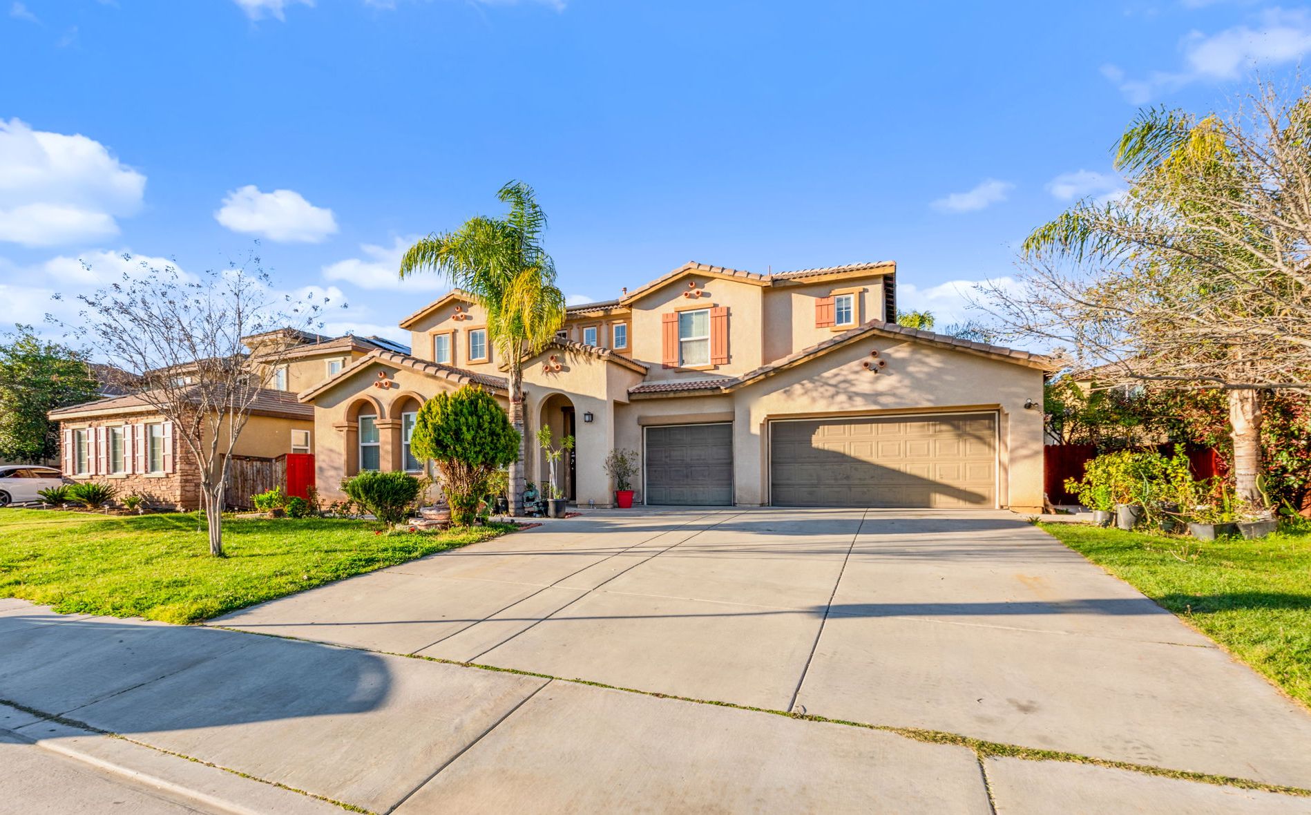 Sunny two-story Mediterranean-style Inland Empire home with a tile roof, palm tree and three-car garage